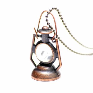 May include: A copper-toned metal lantern pendant necklace with a clear glass window. The chain is silver-toned metal.