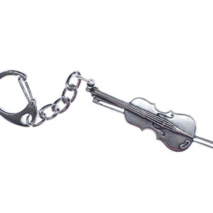 May include: A silver keychain featuring a detailed miniature violin with a silver chain and a silver ring.
