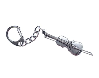 Puede incluir: Un llavero plateado con una miniatura de violín detallada, una cadena plateada y un anillo plateado.