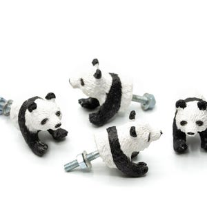 Puede incluir: Cuatro pomos de armario con forma de panda. Los pomos son blancos con marcas negras, que se asemejan a osos panda. Cada pomo tiene un perno metálico para la instalación. Los pandas están en varias poses, algunos tumbados, otros de pie.