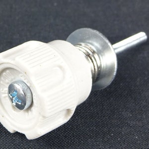 May include: A white ceramic fuse holder with a silver metal screw and a spring. The fuse holder has a threaded end for attaching to a circuit board.