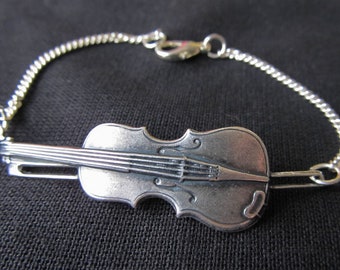 May include: A silver chain bracelet with a silver violin charm. The violin charm is detailed with strings and a scroll.