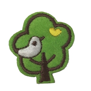 Könnte beinhalten: Ein grüner Filzbaum mit braunem Stamm und Ästen. Ein weißer Vogel mit schwarzem Auge sitzt auf einem Ast. Ein gelbes Herz befindet sich auf dem Baum.