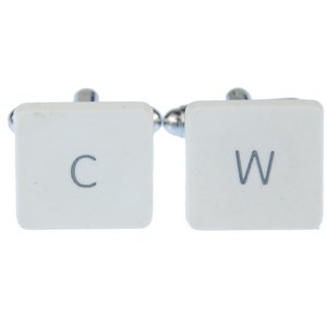 May include: A pair of cufflinks featuring white square faces with the letters "C" and "W" in a gray font. The cufflinks have a silver-colored post and backing.