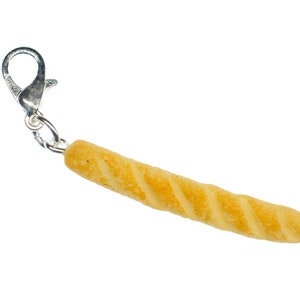 May include: A silver keychain with a small, yellow, bread-shaped charm. The charm is shaped like a baguette and has a slightly textured surface.