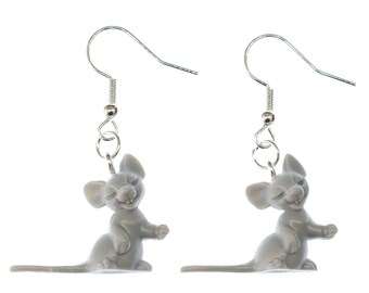 May include: A pair of silver dangle earrings featuring a grey, cartoon mouse charm. The mouse is sitting up with its tail curled behind it.