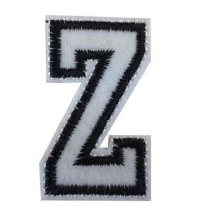 Könnte beinhalten: Ein weißer Filzbuchstabe "Z" Aufnäher mit schwarzer gestickter Umrandung. Der Aufnäher hat einen klassischen College-Buchstaben-Stil, geeignet für Jacken, Taschen oder andere Stoffartikel. Der Buchstabe ist etwa 7.6 cm hoch.