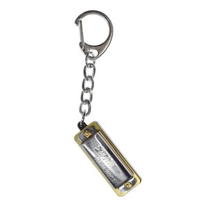 May include: A silver harmonica keychain with a gold trim and the words "Super Harmonica" printed on the front.