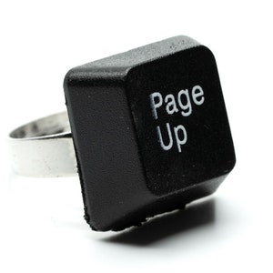 May include: A black ring made from a computer key, with the words "Page Up" in white. The key is mounted on a silver-coloured metal band. The key is square with rounded edges.