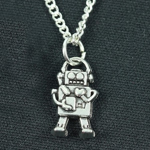 Peut inclure: Collier avec pendentif robot en argent, avec un cœur sur la poitrine. Le robot tient un petit objet dans ses mains.