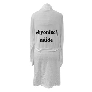 Peut inclure: Robe blanche avec le texte "chronisch müde" imprimé au dos en noir.