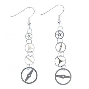 Puede incluir: Un par de pendientes colgantes plateados con una cadena de engranajes y piñones de reloj.