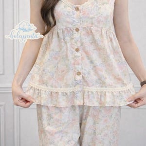 May include: Floral print pajama set in soft pastel colors. The camisole top features a V-neckline with lace trim and wooden buttons. The matching pants complete the set. The brand name "boleysenta" is visible in the image.