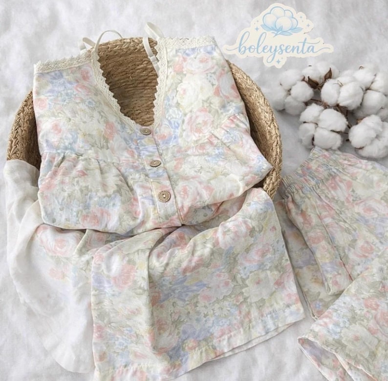 May include: A floral-print pajama set in a woven basket. The set includes a camisole top with lace trim and button closure, and matching shorts. The fabric features a pastel floral pattern in pink, blue, and white. The brand name "boleysenta" is visible.
