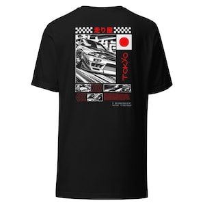 May include: Black t-shirt featuring a graphic design with a car racing through a city. The design includes Japanese text, a red circle, and the word "TOKYO" in red. The shirt also has the text "LAIVIBES" at the bottom.