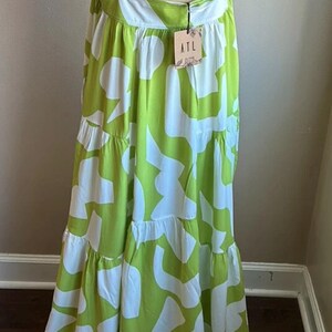 May include: A lime green and white patterned maxi dress with adjustable straps. The dress features a tiered skirt and a flowing silhouette. The tag reads "ATL".