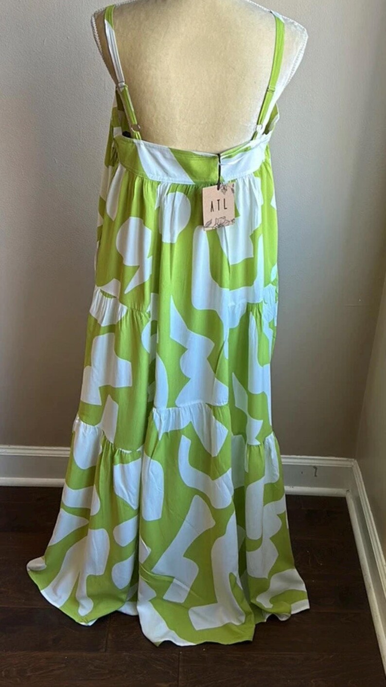 May include: A lime green and white patterned maxi dress with adjustable straps. The dress features a tiered skirt and a flowing silhouette. The tag reads "ATL".