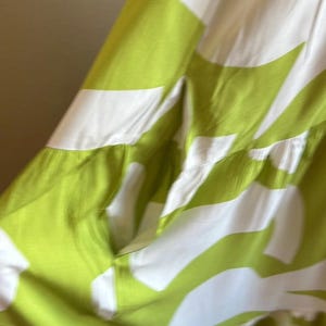 May include: A flowing dress featuring a vibrant green and white abstract pattern. The dress has a tiered design and a relaxed fit, perfect for warm weather. The fabric appears lightweight and breathable.
