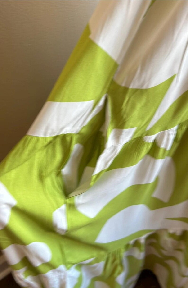 May include: A flowing dress featuring a vibrant green and white abstract pattern. The dress has a tiered design and a relaxed fit, perfect for warm weather. The fabric appears lightweight and breathable.