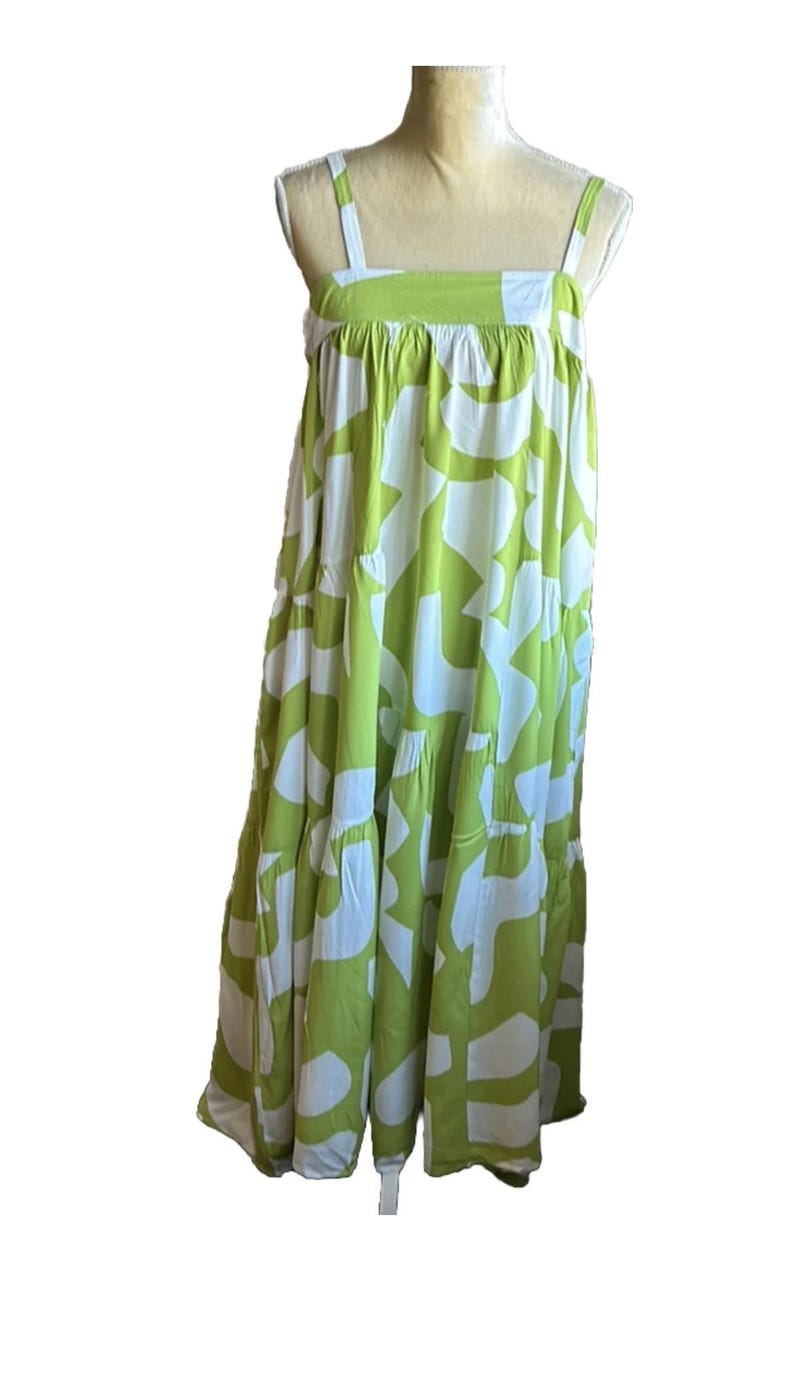 May include: A sleeveless, tiered dress in a vibrant green and white abstract pattern. The dress features wide shoulder straps and a flowing, relaxed fit. The fabric appears lightweight, suitable for warm weather.