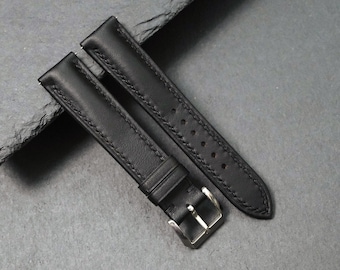 Könnte beinhalten: Schwarzes Leder-Uhrenarmband mit silberfarbener Schnalle. Das Armband hat detaillierte Nähte an den Kanten und Löcher zur Anpassung. Das Uhrenarmband ist für einen klassischen und zeitlosen Look konzipiert.