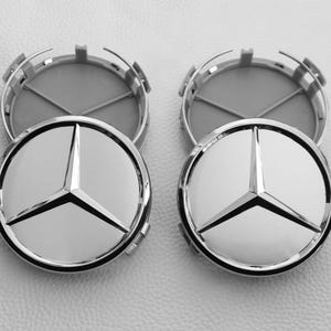 Puede incluir: Cuatro tapacubos Mercedes-Benz plateados y negros. Cada tapacubo presenta el icónico emblema de la estrella de tres puntas en el centro. Los tapacubos son circulares con una superficie brillante y reflectante y un respaldo gris mate.