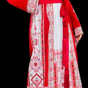 May include: A long, flowing dress with intricate embroidery in red and white. The dress features a red sash at the waist and red sleeves with detailed patterns. The design includes floral and geometric motifs, creating a vibrant and cultural aesthetic.