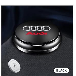 以下が含まれることがあります： 白と赤のアウディのロゴが入った黒い車の芳香剤。丸い芳香剤はシルバーのトリムで、横に白いディスクがあります。「BLACK」という言葉は白い長方形の中にあります。