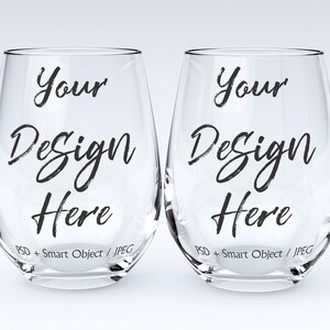 May include: Two clear glass wine glasses with the text "Your Design Here" printed on each. The text is in a black, handwritten font.