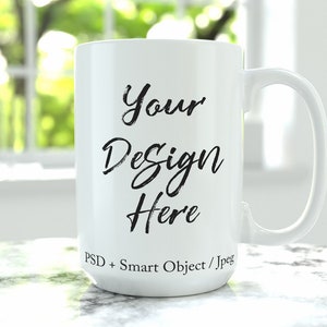 May include: White ceramic mug with a black inscription that reads "Your Design Here" and "PSD + Smart Object / Jpeg".