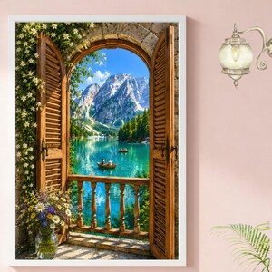May include: A framed print depicts a scenic view through an arched window with wooden shutters. The view showcases a turquoise lake, mountains, and boats. A vase of flowers sits on the balcony, and the frame is white.