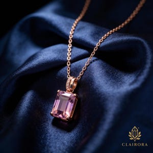 May include: A rose gold necklace featuring a rectangular, light purple gemstone pendant. The pendant is set in a rose gold frame and hangs from a delicate chain. The necklace is displayed on a dark blue satin fabric.