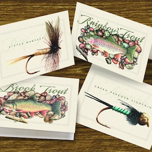 May include: Four cards with illustrations of trout and fishing flies. The cards feature a rainbow trout, a brook trout, a green peacock lightning fly, and a little marlatt fly.