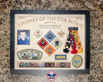 May include: Framed Cub Scout memorabilia display. Features a photo, badges, and text reading "2011 Journey of the Cub Scout 2014" and "Griffin Wright." Includes a black frame and the text "Officially Licensed."