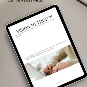 Peut inclure: Une tablette numérique affichant un document intitulé VISION METHOD avec le texte CONSTRUIS UNE VISION CLAIRE POUR CRÉER UNE VIE QUI TE RESSEMBLE. L'écran présente un guide pour définir une vision et une image de mains tapant sur un ordinateur.