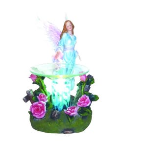 May include: A decorative angel figurine with outstretched wings and a flowing blue gown. The angel stands above a glass dish surrounded by pink roses and green foliage. The base has a built-in light.