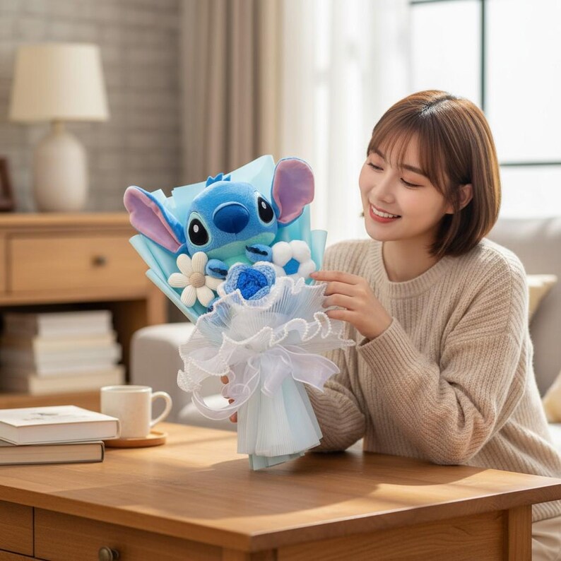 Puede incluir: Un ramo de peluche de Stitch. El ramo presenta un peluche azul de Stitch, flores de tela blancas y azules, y est&aacute; envuelto en papel azul claro y tul blanco. Una idea de regalo &uacute;nica.