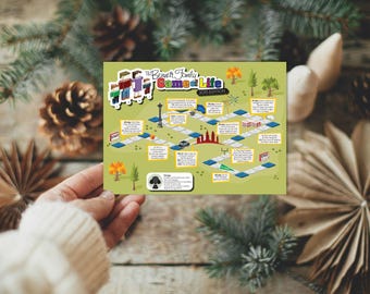 May include: A game board titled "The Bennett Family Game of Life 2015 Edition" is held in a person's hand. The board features a path with various illustrated spaces, including trees, buildings, and a car. The background includes pine branches and decorative elements.