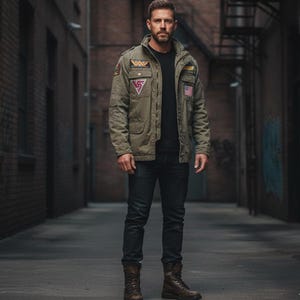 May include: An olive green military-style jacket with patches, worn over a black t-shirt and dark jeans. The jacket features a collar, multiple pockets, and a US flag patch. Brown leather boots complete the outfit, creating a rugged, urban aesthetic.