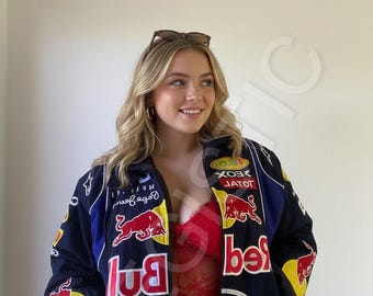 May include: A navy blue and red racing jacket with various logos and text, including "Red Bull" and "Infiniti". The jacket has yellow and white accents and a blue collar. Sunglasses are perched on top.