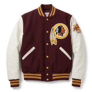 May include: A burgundy varsity jacket with cream-coloured sleeves, featuring a circular patch on the chest with a profile illustration of a person wearing a headdress and two feathers. The jacket has yellow snap buttons and striped ribbed trim.