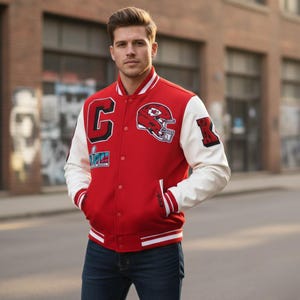 May include: Red and white letterman jacket with the Kansas City Chiefs logo and Super Bowl patch. The jacket has a button-up front, white sleeves, and a red body. The jacket is worn with blue jeans.