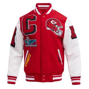May include: Red and white varsity jacket with the Kansas City Chiefs logo and Super Bowl LVII patch. The jacket features a large "C" and the word "Chiefs" in yellow. The sleeves are white, and the jacket has a button-up front.