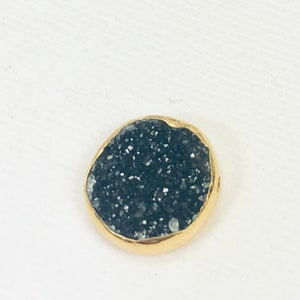 May include: A round, black, sparkly, gemstone pendant with a gold rim.