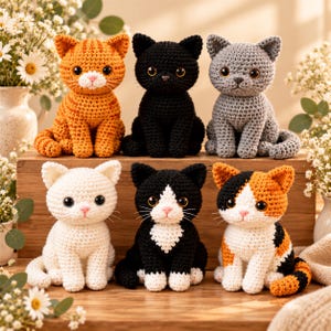Puede incluir: Seis figuras de gatos tejidas a ganchillo dispuestas en dos filas. La fila superior presenta un gato atigrado naranja, un gato negro sólido y un gato gris. La fila inferior incluye un gato blanco sólido, un gato esmoquin y un gato calicó.