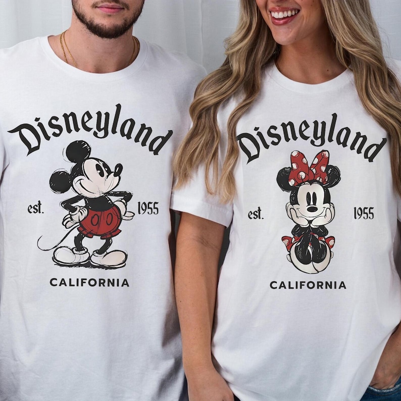 May include: White t-shirts featuring Mickey and Minnie Mouse. Each shirt has the word "Disneyland" above a cartoon character, with "est. 1955" and "CALIFORNIA" below. Mickey wears red shorts, and Minnie has a red bow.
