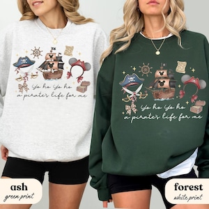 Puede incluir: Dos sudaderas, una gris ceniza y otra verde bosque, cada una con un diseño de temática pirata. El diseño incluye un barco pirata, un sombrero pirata y el texto "Yo ho Yo ho a pirate's life for me."