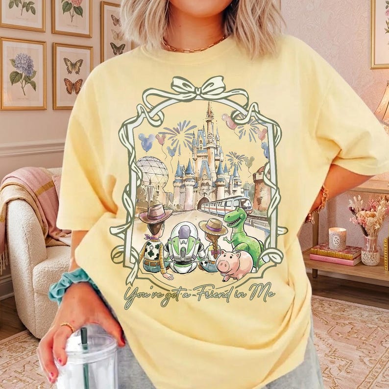 K&ouml;nnte beinhalten: Hellgelbes T-Shirt mit einem Disney-Motiv und dem Text "You've got a Friend in Me". Die Grafik zeigt Charaktere und ein Schloss. Das T-Shirt hat kurze &Auml;rmel und eine lockere Passform.