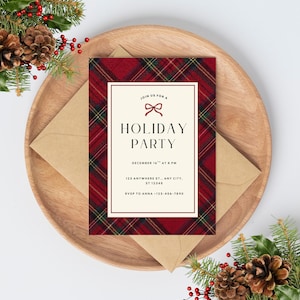 Op de afbeelding: Een uitnodiging voor een vakantiefeest met een rood ruitpatroon en een crèmekleurige rand. De uitnodiging, met de tekst "HOLIDAY PARTY", ligt op een houten bord met een kraft papieren envelop. Denappels en groen omringen het bord.