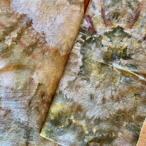 May include: Two rectangular fabric towels featuring an organic, mottled pattern in earthy tones of olive green, muted brown, soft yellow, and cream. The surface displays a textured, botanical-inspired print with irregular shapes and blended color gradients.